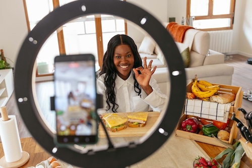 Black woman influencer creating video content for recipe with sandwiches, using a ring light Why Different Rules Apply To The South African Media Landscape